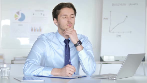 Thoughtful Businessman Writing in Office