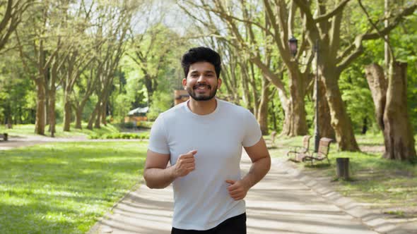 Positive Arabian Man in Active Outfit Jogging at Green Summer Park