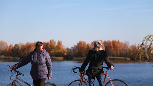 Friends Walking with Bicycles Near the River