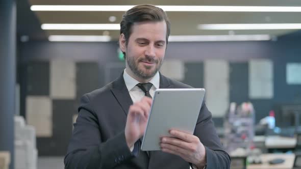 Portrait of Businessman Celebrating on Tablet in Office