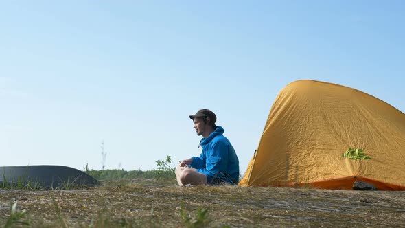 Guy in Jacket Grinds Coffee Near Yellow Tent on Spring Day