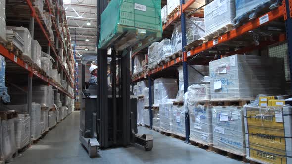 Forklift Lifts a Large Box on the Top Shelf