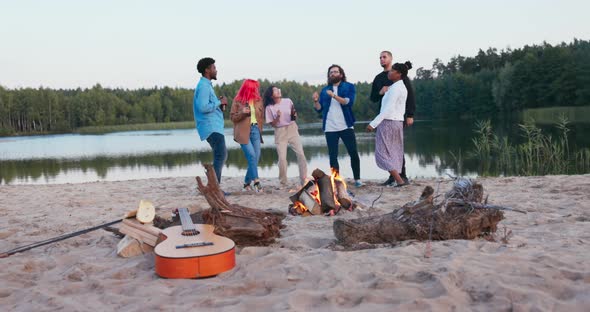 Friends are Dancing Party on the Beach By the Lake Until Morning Early Dawn Campfire is Burning