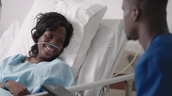 The Patient Smiles at the Good News From the Doctor Lying Under the IV and Breathing Apparatus
