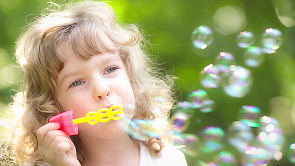 Happy Child Playing With Soap Bubbles