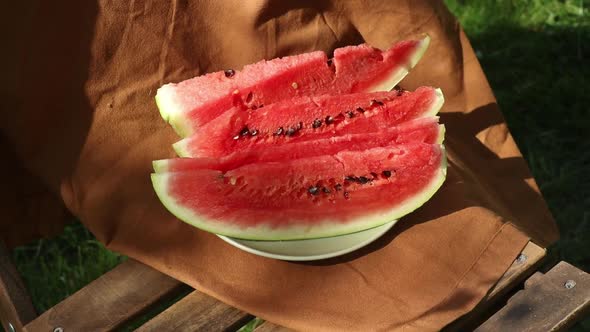 Sliced watermelon on brown cloth and wooden chair in garden