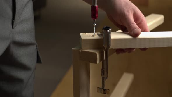 C-clamp holds pine lumber in place as screw is driven with screwdriver