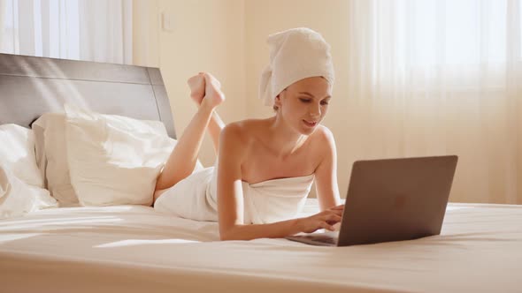 Pleasant Woman Resting on Bed and Using Modern Laptop