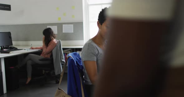 Happy african american woman using smartphone in office and greeting business colleague