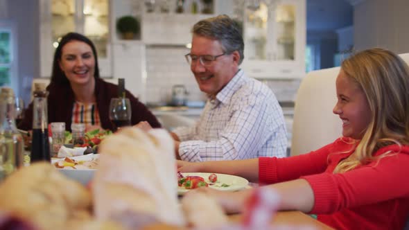 Happy caucasian multi-generation family playing with smartphone at table during family meal