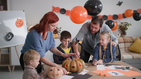 Family of 5 Prepares for Halloween at Home Parents Help Children to Make Decorations with Pumpkins