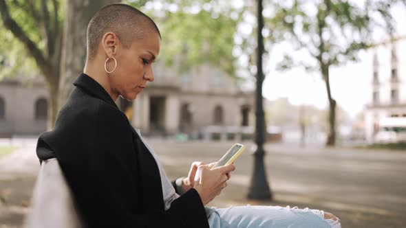 Concentrated bald woman typing by phone