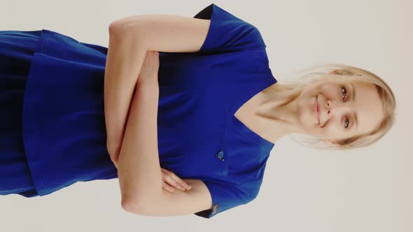 Vertical Shot Positive Blonde Healthcare Worker Woman in Dark Blue Uniform Looking at Camera and