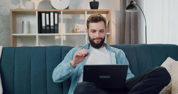 Guy Sitting in Relaxed Pose on Soft Couch at Home and Satisfied from Results