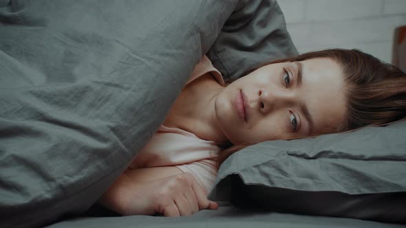 Indifferent Young Lady Looking At Camera Lying In Bed Indoor