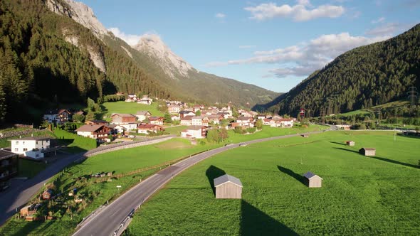 Aerial View of an Austrian Village in a Green Mountain Valley at Sunset Alps