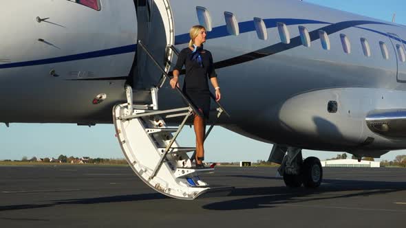 SLOMO: A playful flight attendant walks down the stairs of an aircraft.