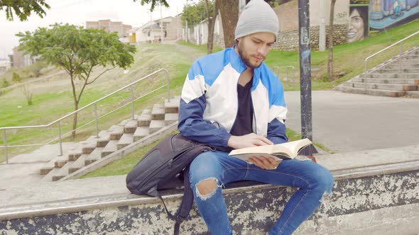 Young boy reading a book on the street