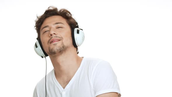 Young Handsome Man Smiling Listening Music in Headphones Dancing Over White Background