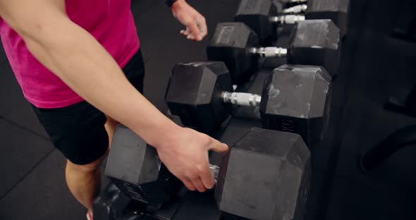 Male Hands Taking Bodybuilding Dumbbells In Gym Club. Closeup Man Hands