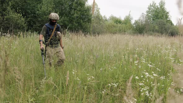 In the Field a Sapper Uses a Mine Detector