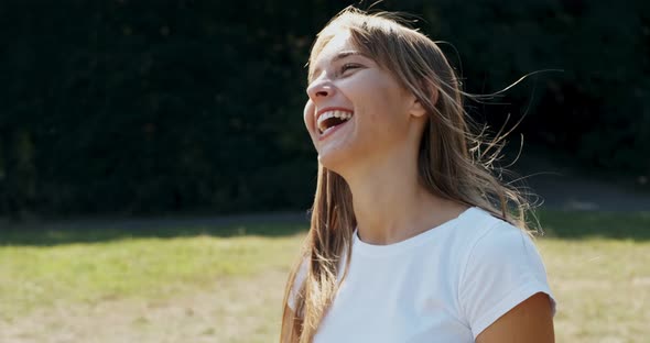 Portrait of Young Female Who Smiling and Looking at the Camera on Green Lawn. Cheerfuly