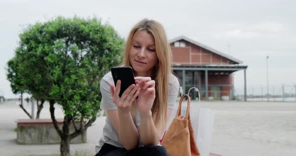Young happy woman using smartphone at the park.
