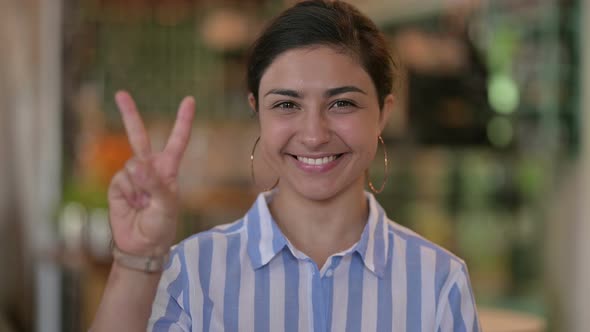 Appreciative Young Indian Woman Showing Victory Sign 