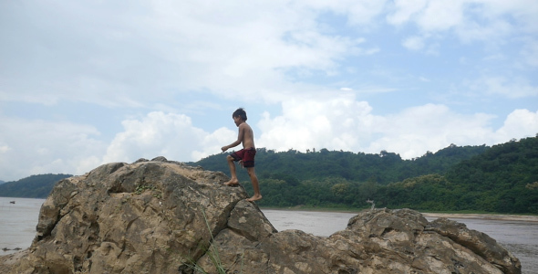 Asian Kid Walking To Top Of Rock