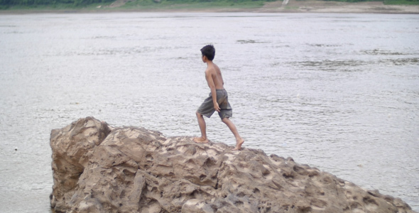 Boy Walking On Rock In A River