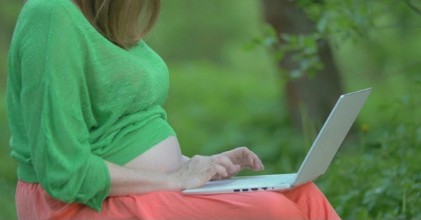 Pregnant Woman With Laptop On Her Knees