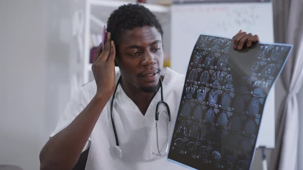 Portrait of Expert African American Neurologist Pointing at Xray Talking in Video Chat