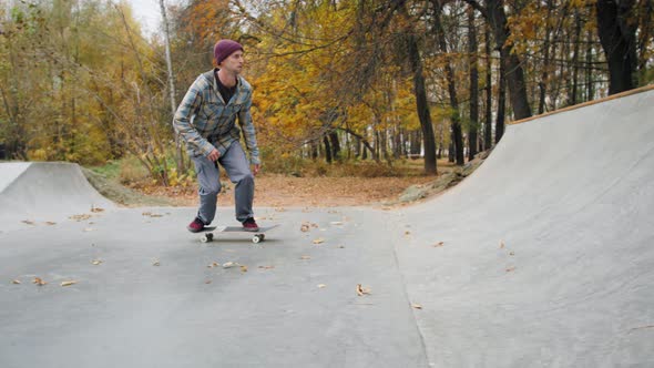 Skater Practicing in the Autumn Concrete Skate Park Making Tricks and Rides in Ramp
