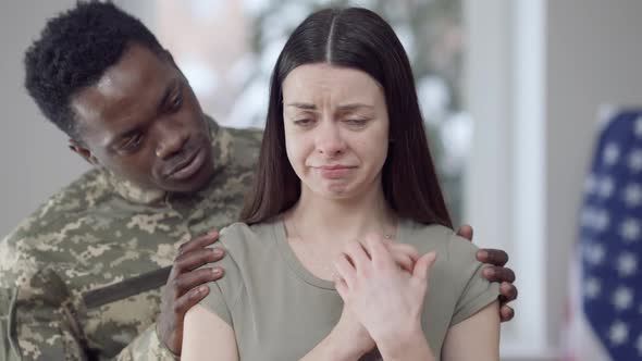 Portrait of Crying Young Beautiful Caucasian Woman with African American Military Man Calming Down