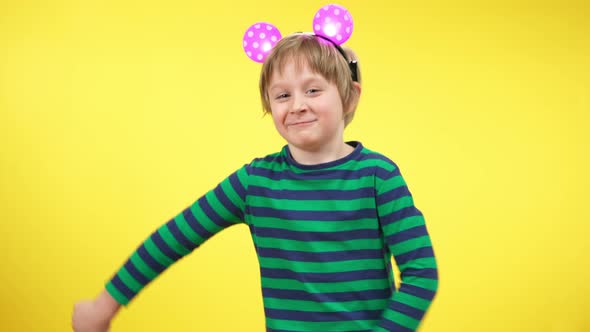 Funny Dance of Cheerful Little Boy Wearing Toy Mouse Ears at Yellow Background