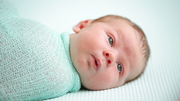 Blue-eyed Newborn Baby Lying And Looking Around In