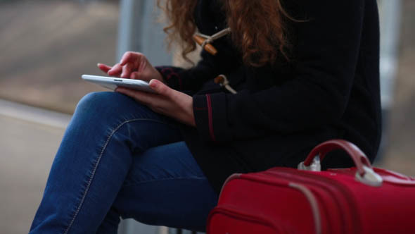 Girl at the Railway Station Uses the Tablet