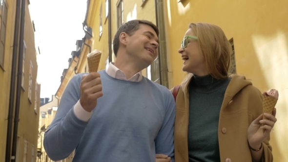 Happy Man And Woman Eating Ice-cream During a Walk
