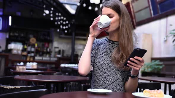 Beautiful Woman Using Phone In Cafe, Drinking Coffee