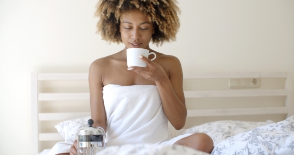 Attractive Woman With A Cup Of Coffee On The Bed