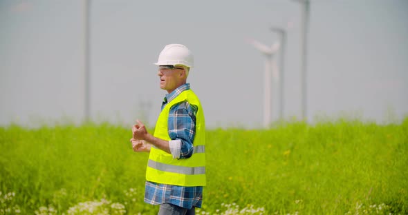 Engineer Directing By Windmills in Farm Against Sky