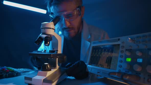 A Man Scientist is Looking Into Microscope Biochemical Research