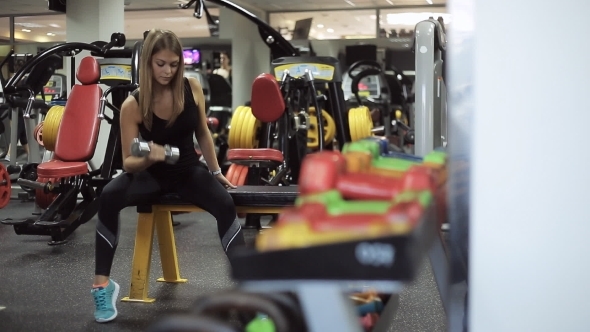 Athletic Blond Dumbbell Raises Biceps In The Gym.