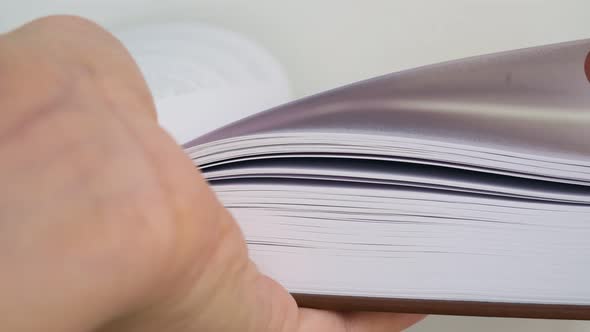 Closeup of a Paper Book Lies on the Hand Its Pages are Turned Over with the Other Hand and Fingers alt