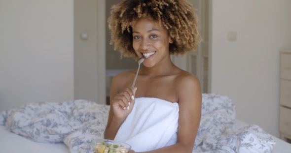 Young Woman On Bed Eating Vegetable Salad