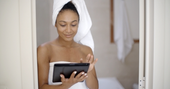 Woman Wearing Bath Towel Using Tablet Computer