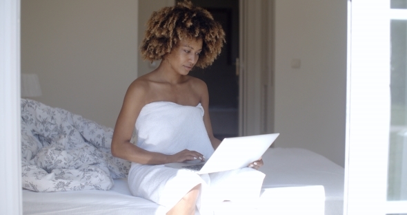 Young Woman Using Laptop On Bed