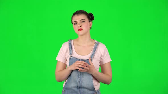 Cheerful Female Listens Attentively and Nods His Head Pointing Finger at Viewer Against Green Screen