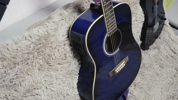 Acoustic and Electric Guitars Lie on a Sofa Inside a Room With a Home Interior