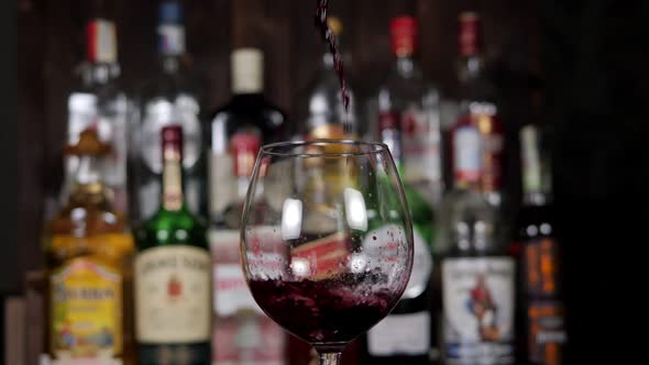 Closeup of a Bartender Pouring Red Wine From a Bottle Into a Glass in a Bar